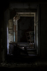 A dark corridor in an abandoned building. Vertical photo of a cluttered corridor in ruins. Abandoned building. Horror. Dark room.