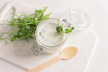 Sour milk product drink with the addition of fresh micro grass sprouts greens on a white kitchen table.