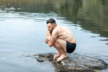 a person suffering from cold stands on a stone around water and nature