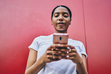 Below view of dark skinned female blogger using mobile phone and 4G connection for online chatting and networking with friend.African American woman using smartphone. Texting message in social network