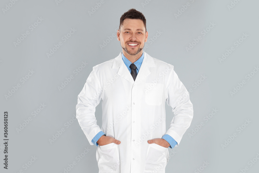 Wall mural Happy man in lab coat on light grey background