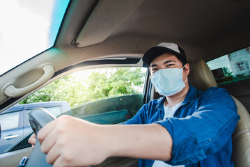 A young Asian man is a professional driving a package delivery car. Wear a medical mask Asians work to drive online deliveries to home. There is a parcel box in the car.