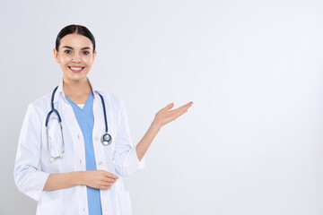 Portrait of young doctor with stethoscope on white background