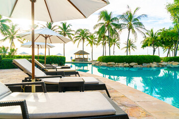 Umbrella and chair around swimming pool in resort hotel for leisure travel and vacation neary sea ocean beach