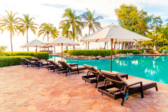 Umbrella and chair around swimming pool in resort hotel for leisure travel and vacation neary sea ocean beach