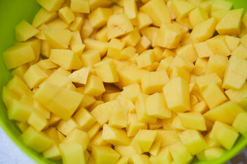 Fresh potatoes in pieces in green utensils. Close-up