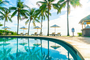 Beautiful luxury umbrella and chair around outdoor swimming pool in hotel and resort with coconut...
