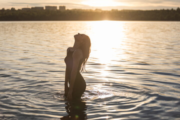 girl in water on a sunset background in warm colors, silhouette