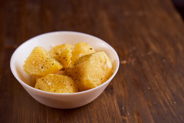 Boiled potatoes with mslom seasonings in a plate on a brown background