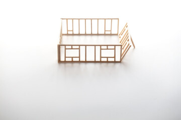 Building a house or a home. Frame work of a house (miniature model) isolated on neutral white with natural shadows.