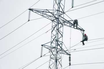 Male electricians make repairs on the electric tower. Power line against the sky.June 6, 2020 Saint-Petersburg, Russia