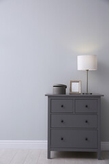 Modern grey chest of drawers near light wall in room. Interior design
