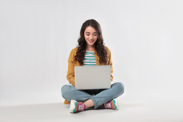 Young woman sitting with laptop on white background