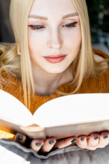 close-up portrait of a young cute blonde girl with a book in her hand