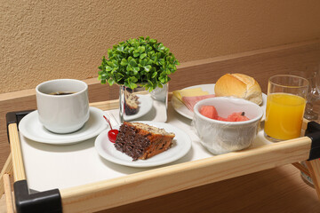 Table with breakfast, orange juice, chocolate and brigadeiro cake, mozzarella cheese and ham and fruits
