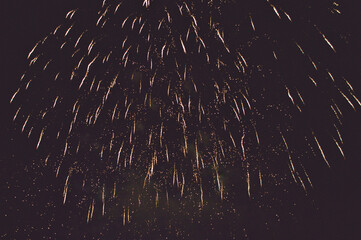 Rain from sparks from a fireworks display in the night sky conveys a grandiose volume of festive fireworks.
