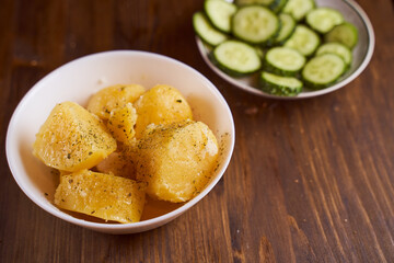 Boiled potatoes with mslom seasonings in a plate on a brown backgroundю With copy space.