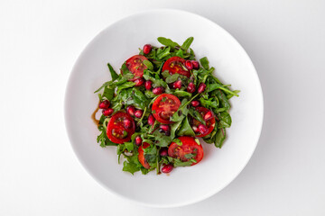 Salad of arugula, cherry tomatoes, pomegranate and sauce top view. Dishes for delivery, online store. Isolated on a white background.