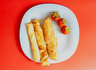 Breakfast, strawberries and pancakes on a blue plate on a red background