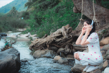 A beautiful Asian female tourist visiting Thailand, she likes to travel naturally. Beautiful forests and waterfalls. Concept: Thai tourism.