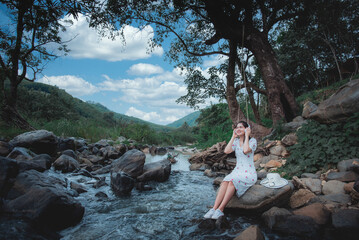 A beautiful Asian female tourist visiting Thailand, she likes to travel naturally. Beautiful forests and waterfalls. Concept: Thai tourism.
