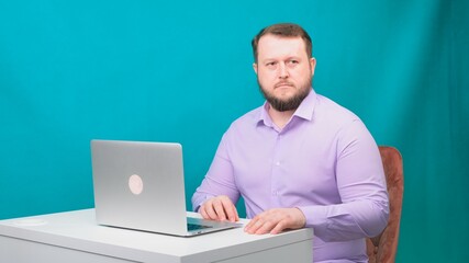 Young happy businessman holds a conference meeting at a laptop, a man is nervous and worried, on a green screen. Portrait of a male talking man looking into his laptop. Man working at his desk in the