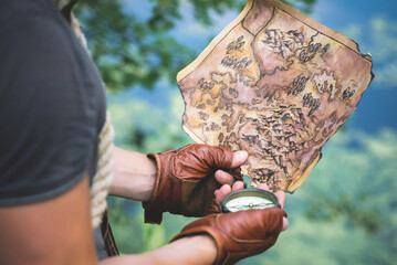 Old map and compass in adventurer hands close up.