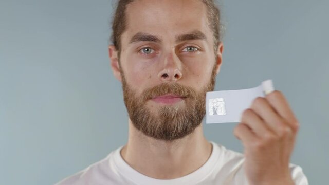Close up face portrait man looking at camera serious and tearing tape from her mouth on grey background human shut silence face fear expressive attitude taboo censorship violence scared slow motion