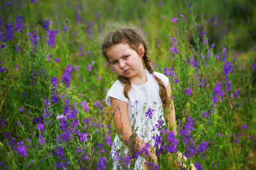 Portrait of a little girl in flowers . Happy child on a walk in the countryside