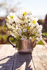 Steel kettle with sprigs of cherry blossoms, pears and apple trees on a natural blurred background