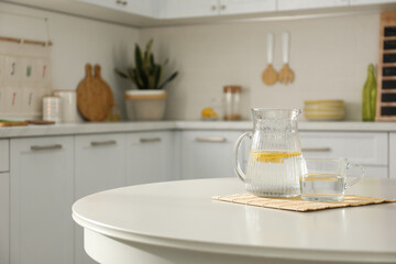 Fototapeta na wymiar Fresh lemonade on white round table in kitchen. Stylish interior design