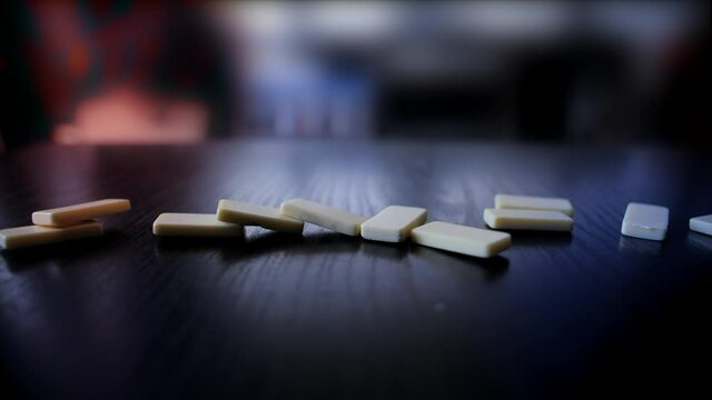 Domino slowly falling on a wooden table shot in slow motion