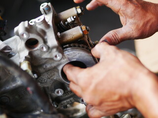 Mechanic working on motorcycle engine in workshop. 