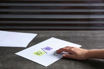 Woman taking paper sheet with 80/20 rule representation at grey table, closeup. Pareto principle...