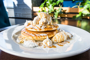 Three pancakes, caramel, almond flakes, Italian meringue, vanilla cream, powdered sugar on a white plate