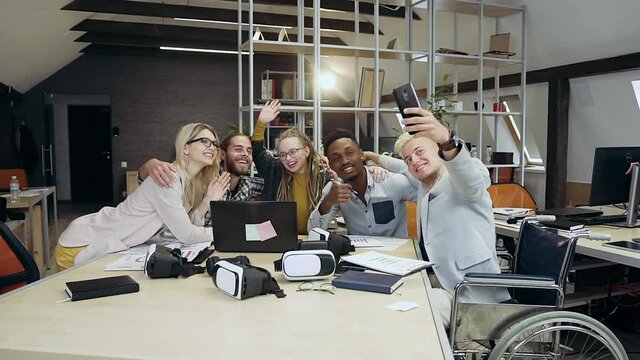 Attractive smiling successful young office people making selfie while working together in contemporary office room,close up