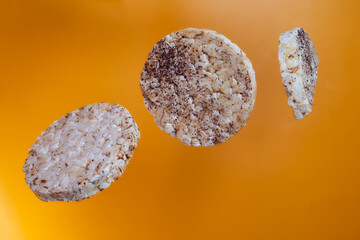 Fototapeta premium Wheat breads fall on orange background. Advertising photo. Close-up