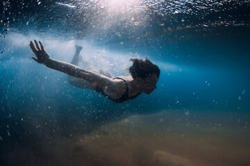 Fototapeta na wymiar Woman dive without surfboard under wave. Underwater duck dive under wave and sandy bottom