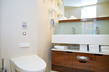 Clean and modern design bathroom with sink, shower, bath tub, towels and mirror and mosaic tiles in...