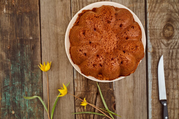 Homemade cupcake with chocolate filling inside on a wooden table with a Yellow Woodland tulips, Wild tulips on a wooden background. Top view.