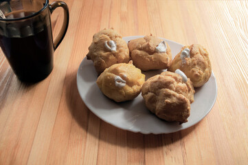 Custard cookies and tea, golden eclair filled with whipped cream
