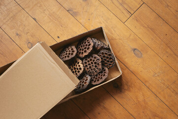 Dried lotus seed pods in a box on an old wooden floor. Flower delivery. Dried flowers for interior decoration and floristry.