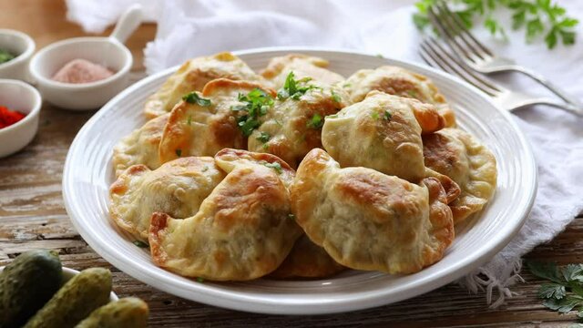 Baked dumplings stuffed with mushrooms and lentils on a white plate on a wooden table, close up view