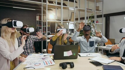 Front view of likable concentrated creative diverse group of colleagues which moving hands on virtual screen using special 3d glasses in contemporary office - Powered by Adobe
