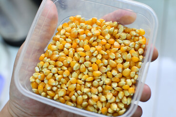 Male adult hand holding bowl full of corn kernel