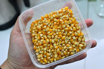 Male adult hand holding bowl full of corn kernel