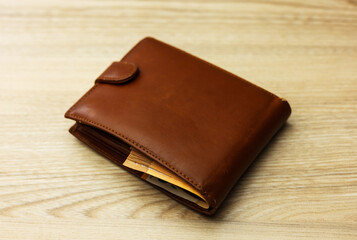 Wallet stuffed with Euro banknotes on the wooden backround