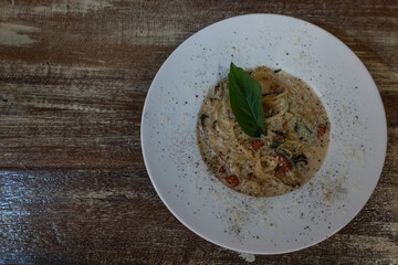 Spaghetti with mushrooms in white cream sauce on wooden table - Italian food. Top view.