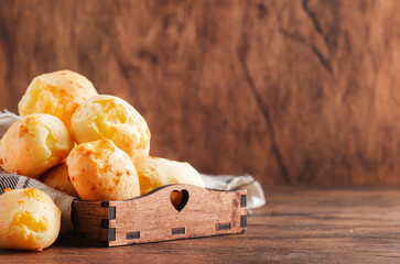 Golden Cheese buns in wooden tray, rustic kitchen table, copy space
