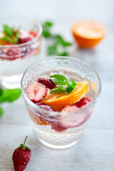 Summer cocktail with strawberry, orange and mint in glass